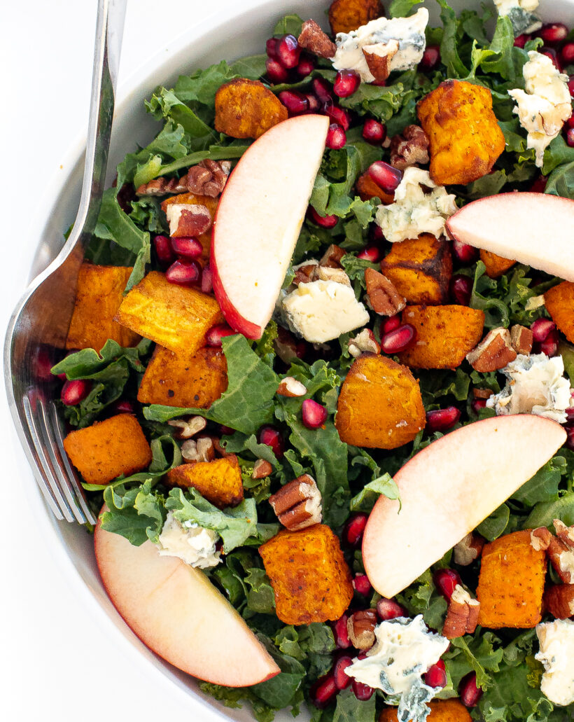 Fall harvest salad in a white bowl with a silver fork on the side.