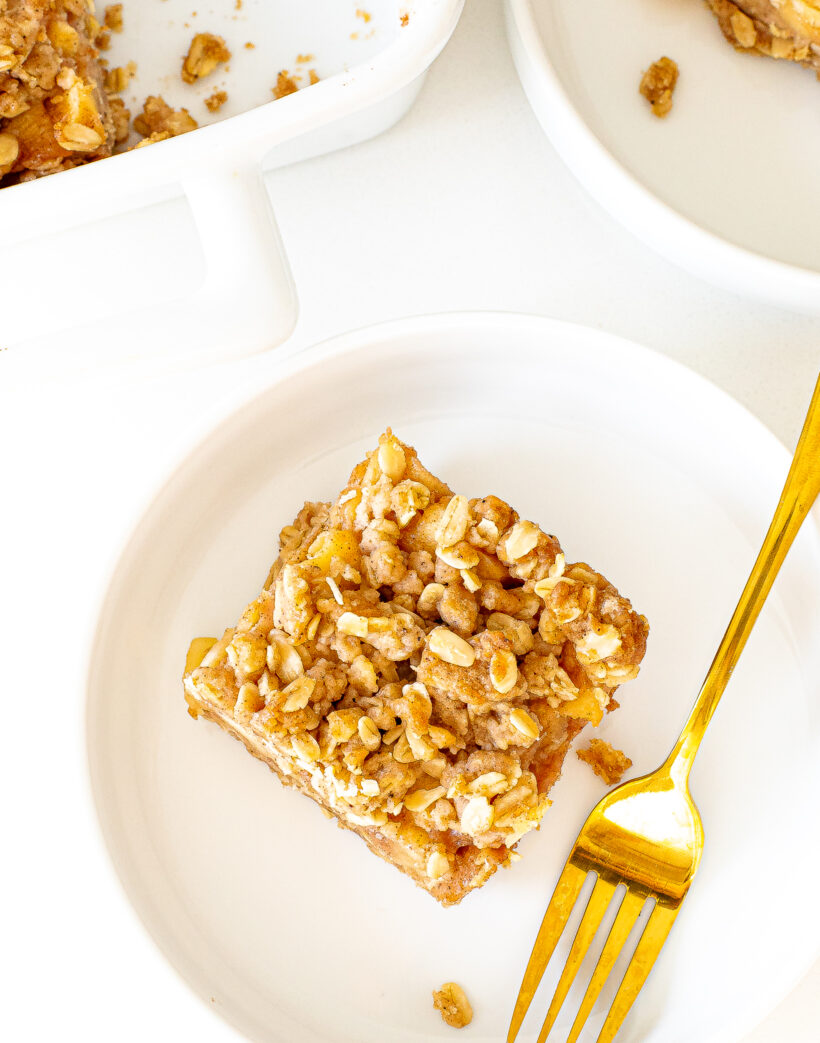 A slice of healthier apple crumb bar on a white plate.