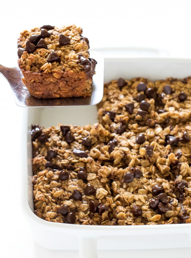 Healthy breakfast baked oatmeal squared scooped up from baking tray on a silver spatula. 