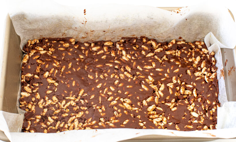 The chocolate mixture and crispy rice pressed into the pan lined with parchment paper.