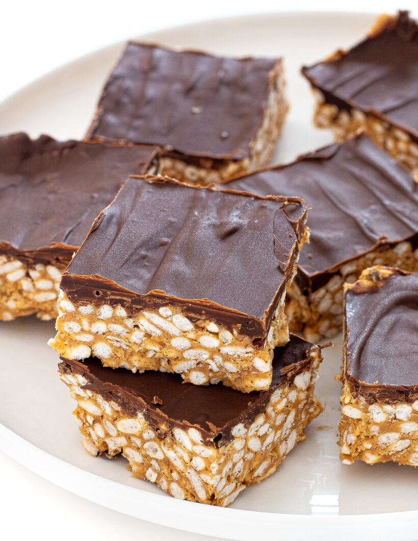 Scotcheroos stacked on top of each other on a white plate. 