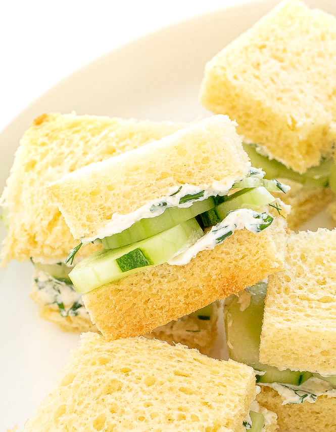 Cucumber sandwiches stacked on a plate.