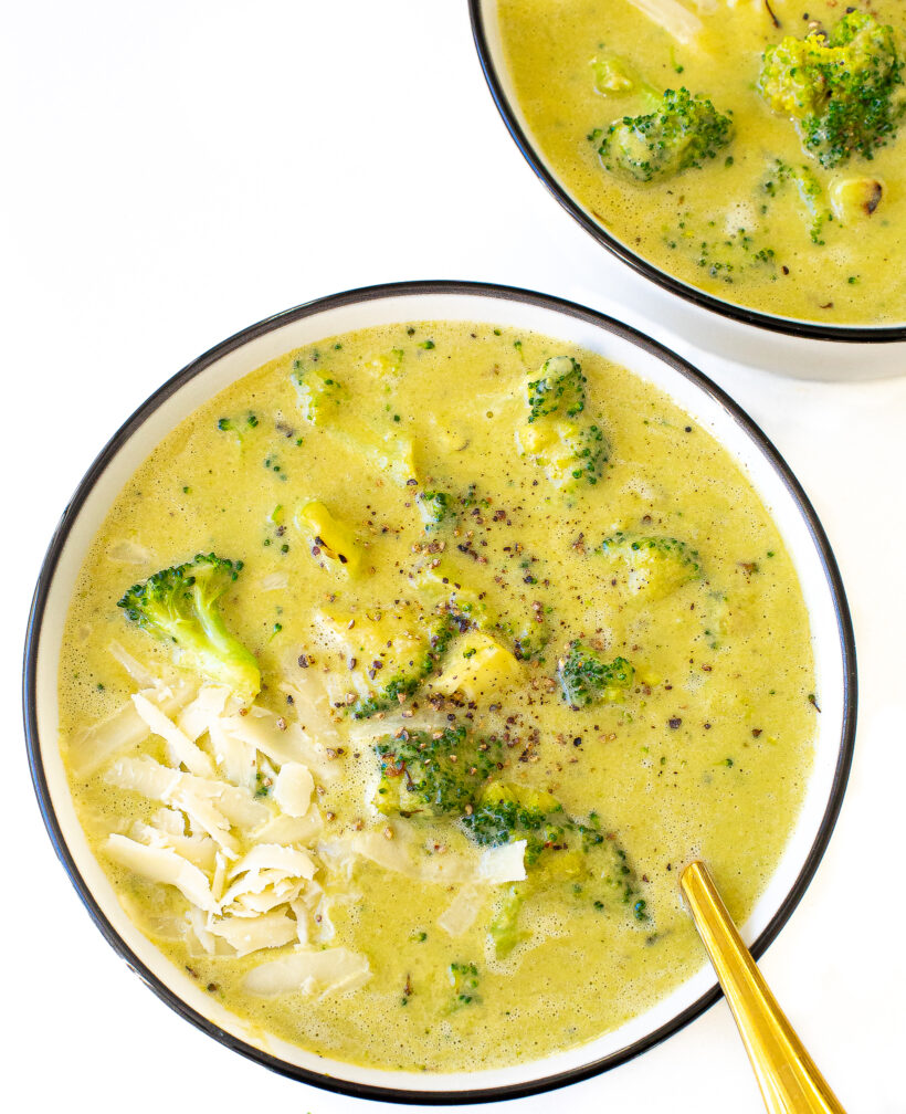 high protein broccoli cheddar soup in white bowl with spoon