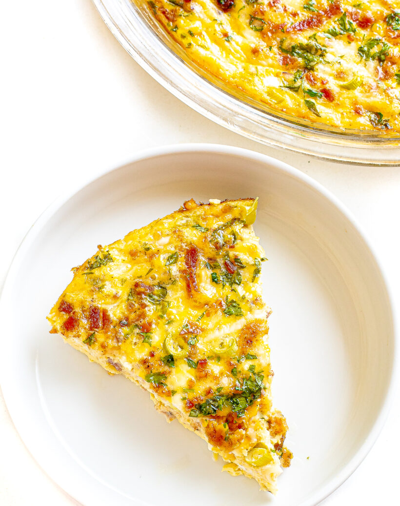 A slice of quiche on a white plate.