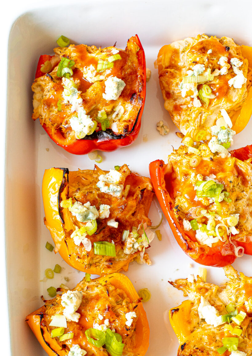 Buffalo chicken stuffed peppers in a white baking dish.