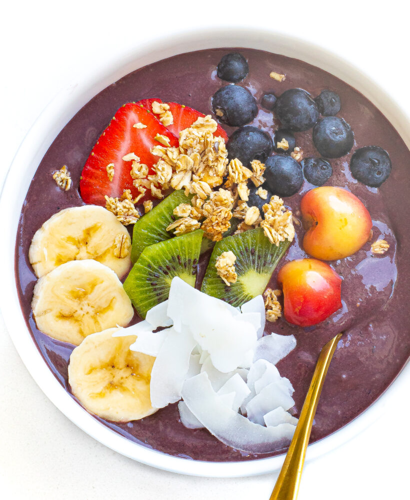 Overhead shot of acai bowl topped with fresh fruits, granola and coconut flakes. 