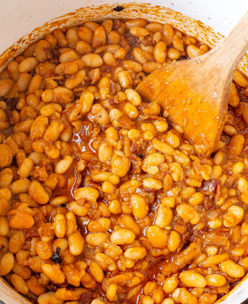 Baked beans in a pot with a wooden spoon.