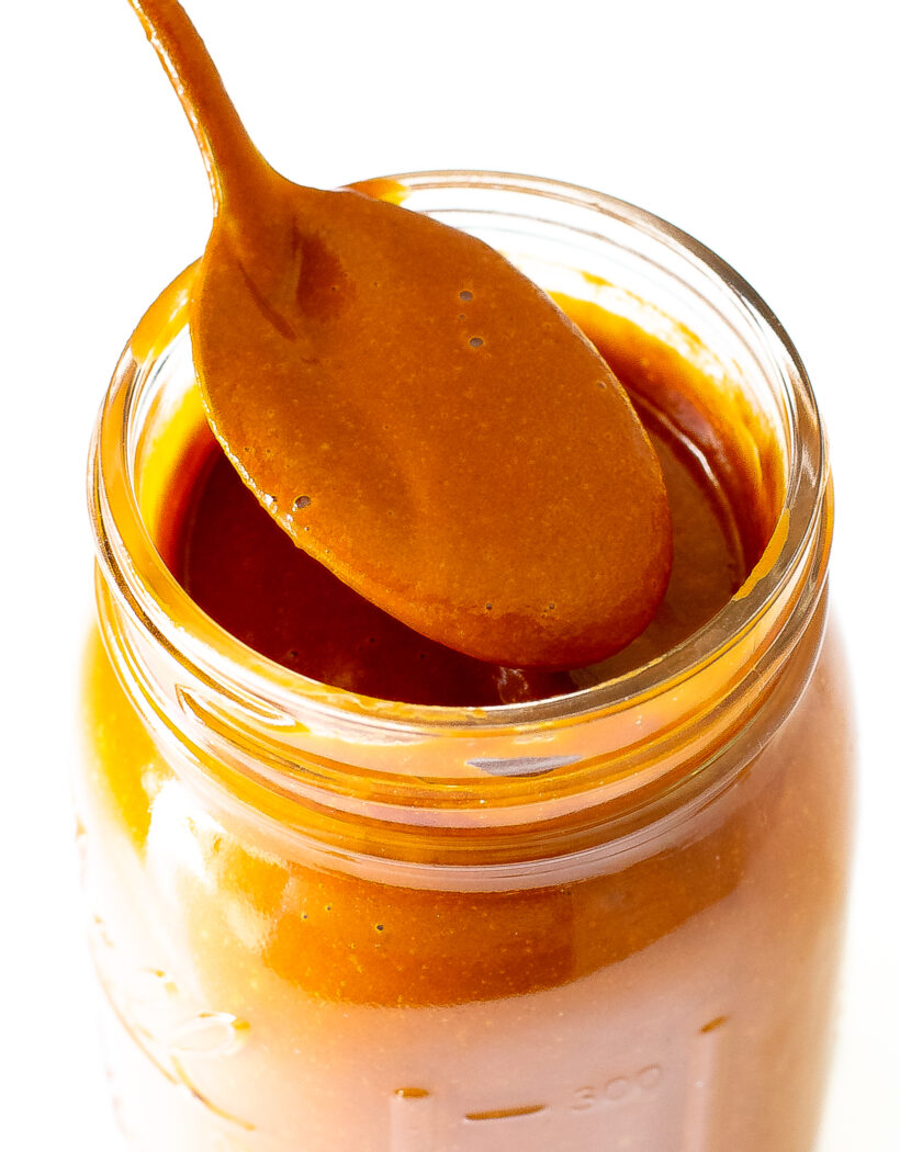A jar of enchilada sauce with a spoon holding some sauce.