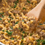 Cooked beef and macaroni pasta in skillet with wooden spoon.