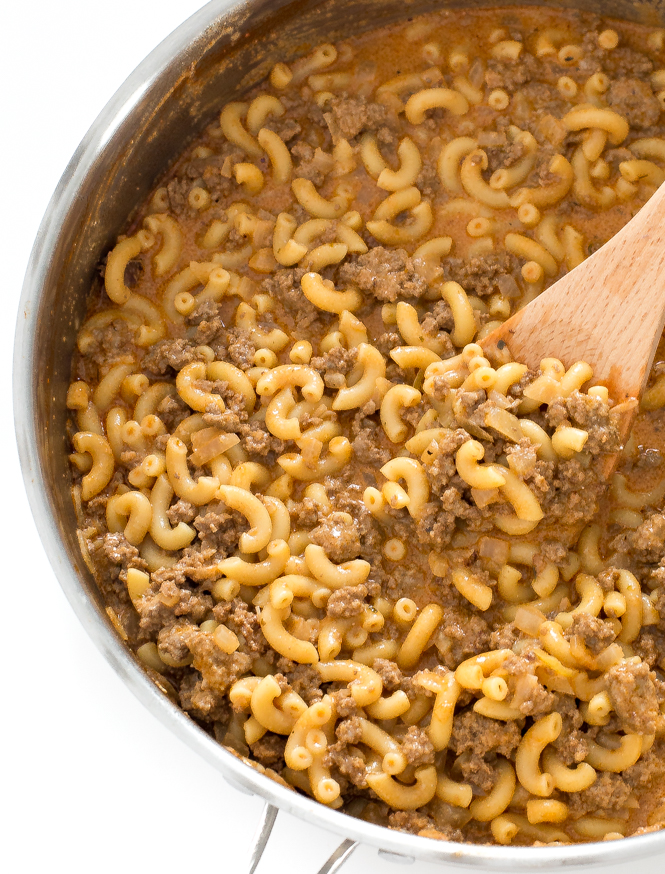 Cooked beef and macaroni pasta in skillet with wooden spoon.