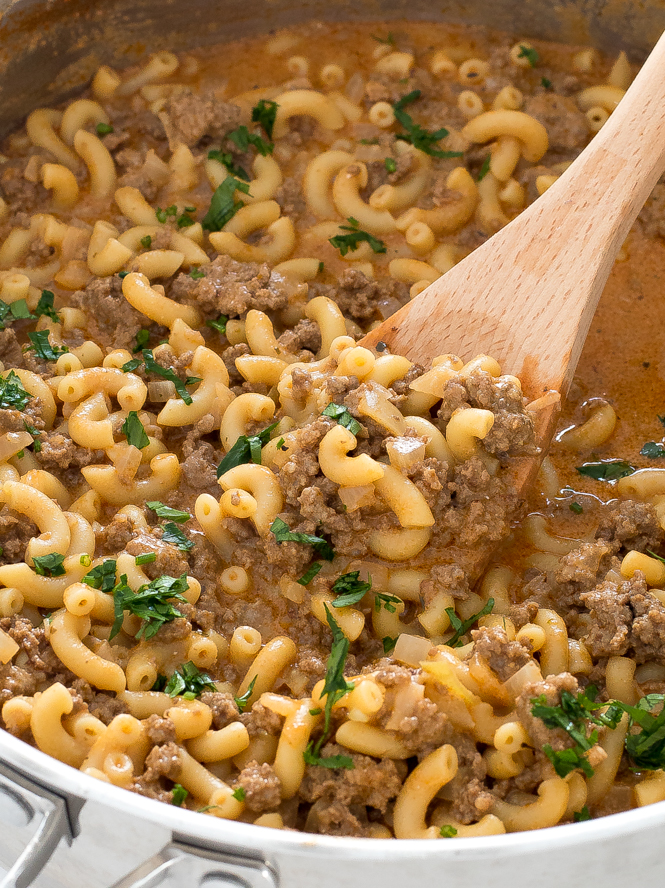 Cooked beef and macaroni pasta in skillet with wooden spoon.