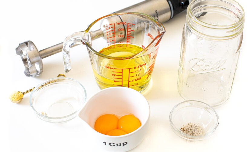 Ingredients for homemade mayo on a white surface.