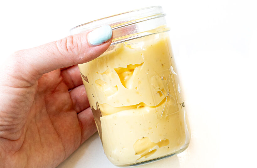 Hand holding jar of homemade mayo.