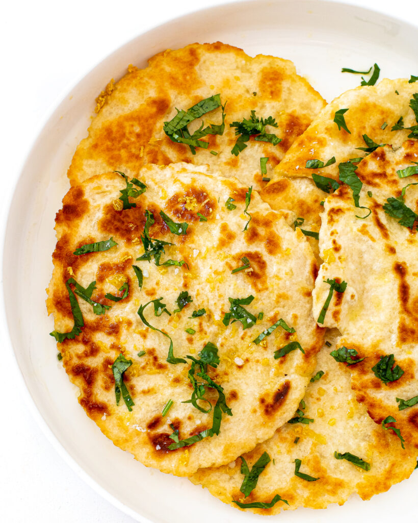 A top down view of naan bread on a white serving plate.