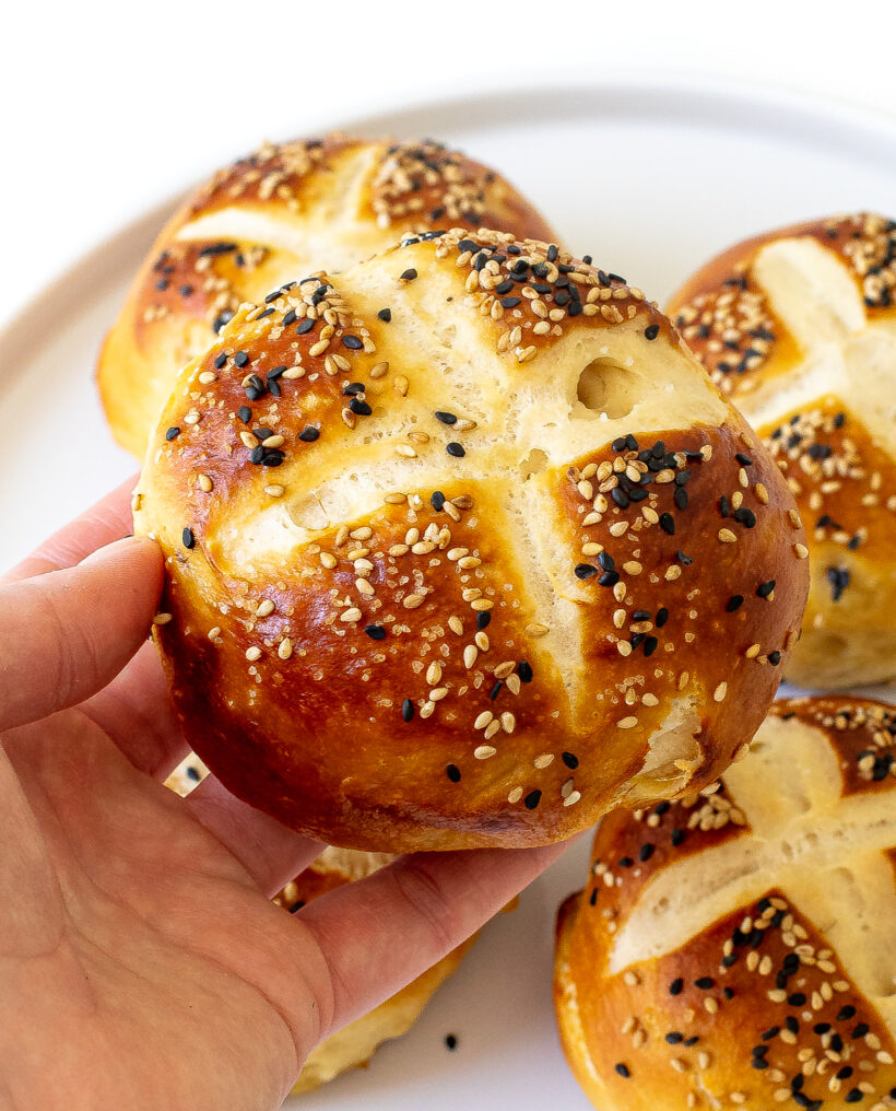 author picking up a homemade burger bun with sesame seeds on it