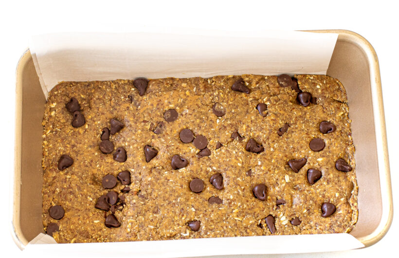 Protein bar mixture pressed into the bottom of a loaf pan. 