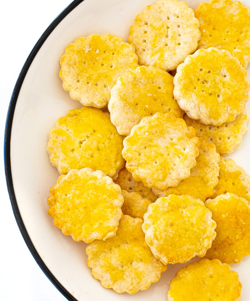 Ritz crackers piled up on a white plate.