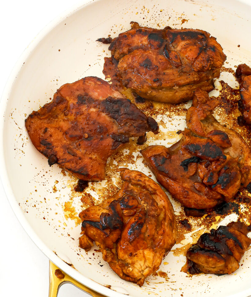 Close up shot of chicken thighs searing in a skillet. 