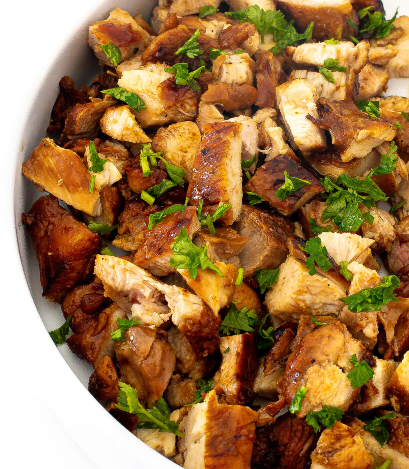 Diced honey chipotle chicken in a bowl garnished with fresh herbs.