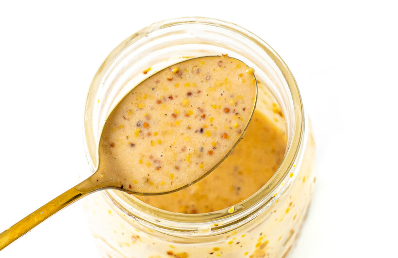 Spoon holding a scoop of honey mustard dressing.