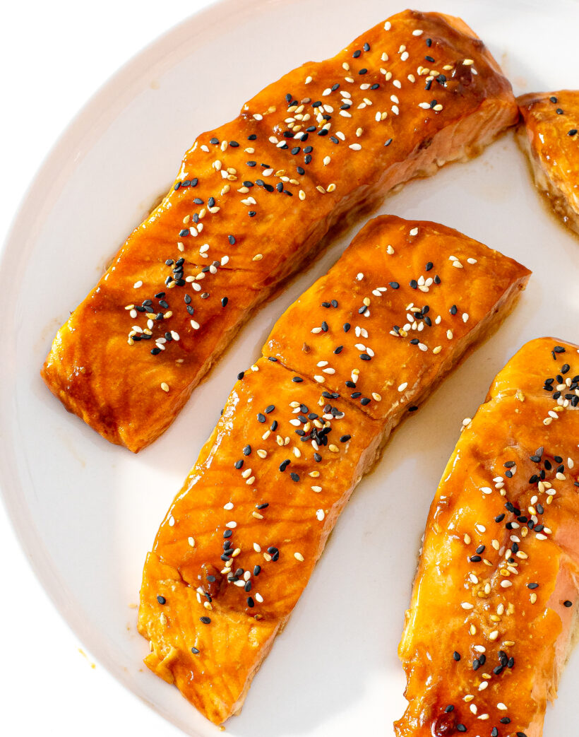 overhead shot of cooked salmon on a plate with honey sriracha sauce on top