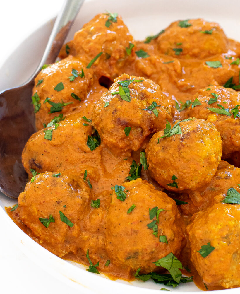 Close up shot of butter chicken meatballs in a bowl.