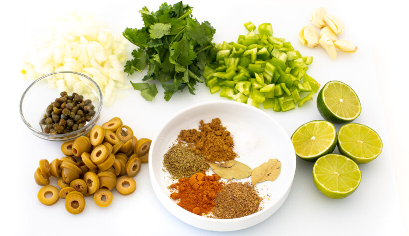 Ingredients needed for arroz con pollo on a cutting board.