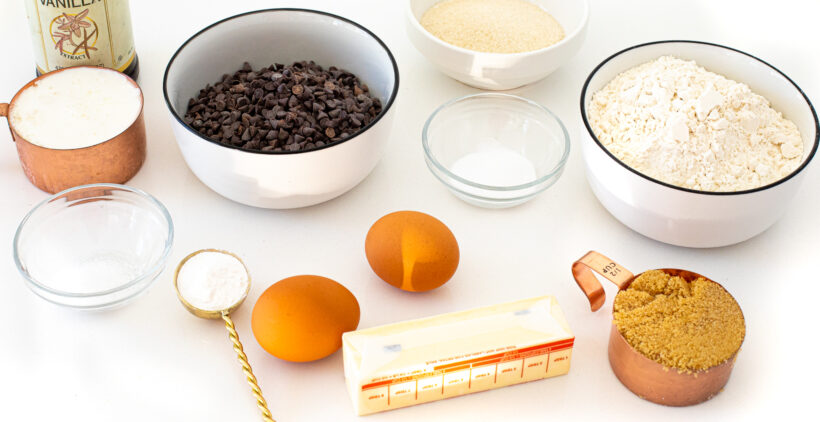 Ingredients for chocolate chip muffins laid out on a white surface.