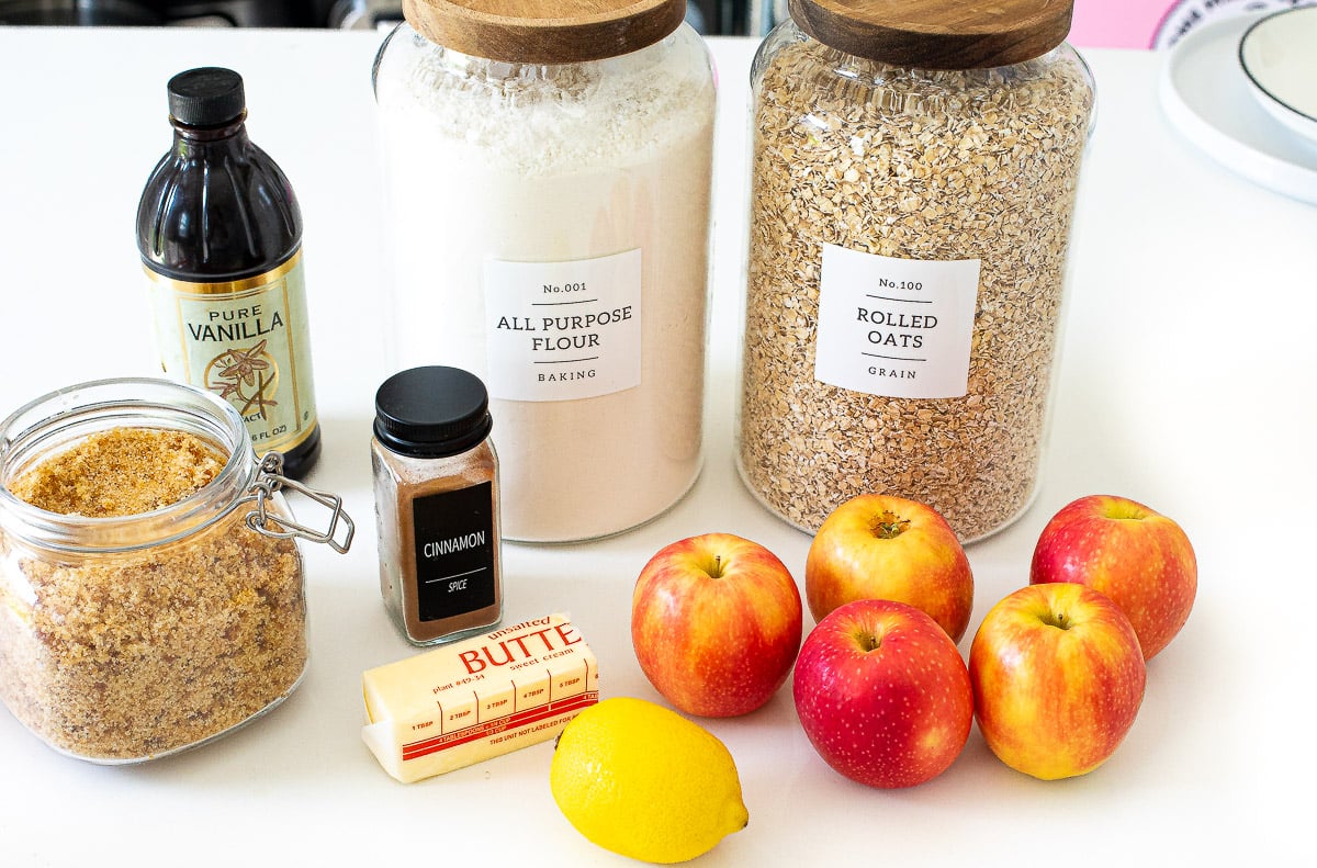 Apples, near brown sugar, oats, flour, a lemon and a stick of butter.