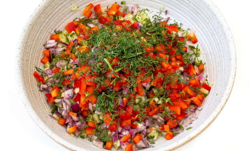 Cucumbers, red onions, bell pepper, and dill in a medium mixing bowl.