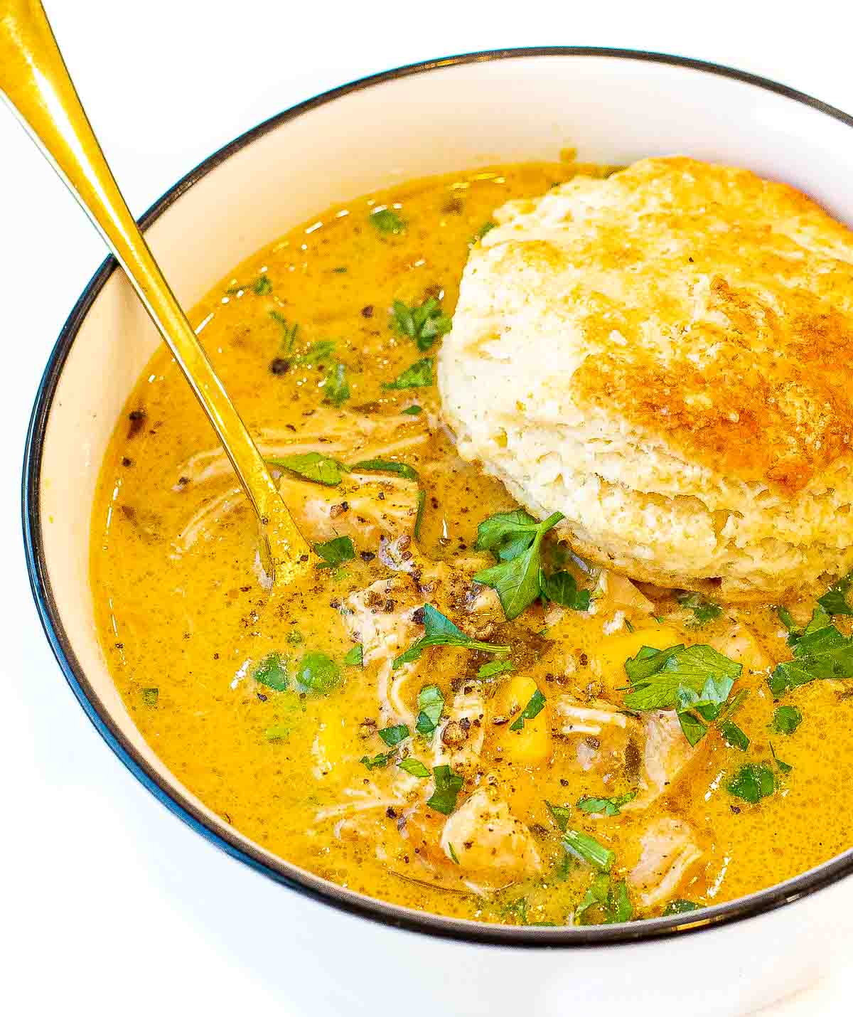 bowl of instant pot chicken pie soup with a buttermilk biscuit on top