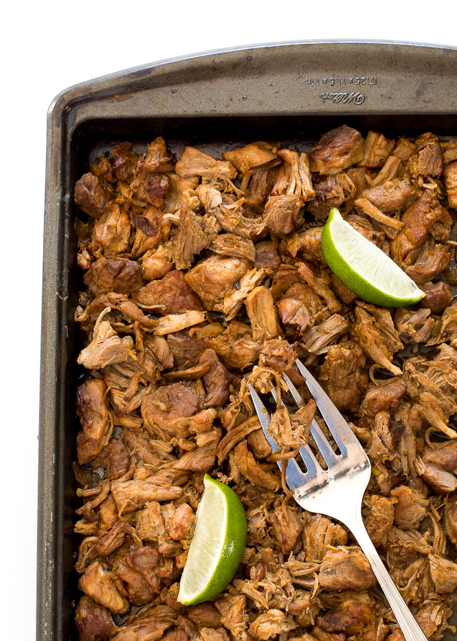 Instant Pot Carnitas in a baking dish with a fork and wedges of lime.