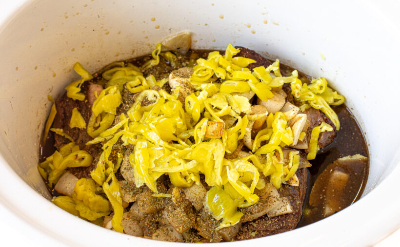 Chuck roast, pepperoncini, broth, onions and garlic in a slow cooker.