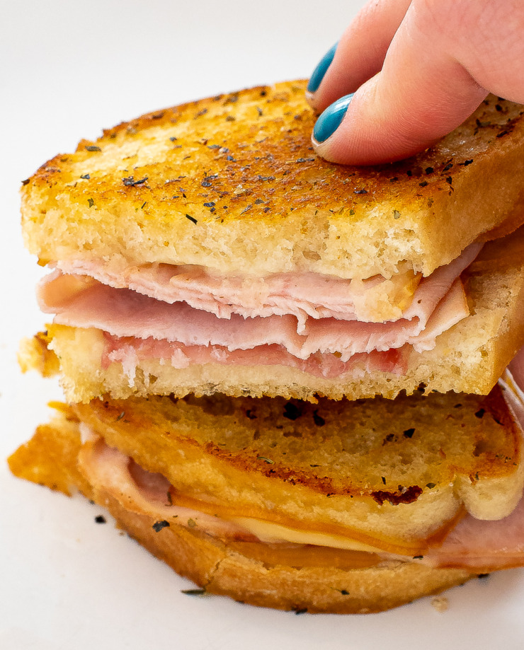 Hand holding one half of a grilled cheese sandwich. 
