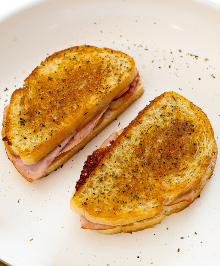 Two grilled cheese sandwiches in a skillet after being cooked. 
