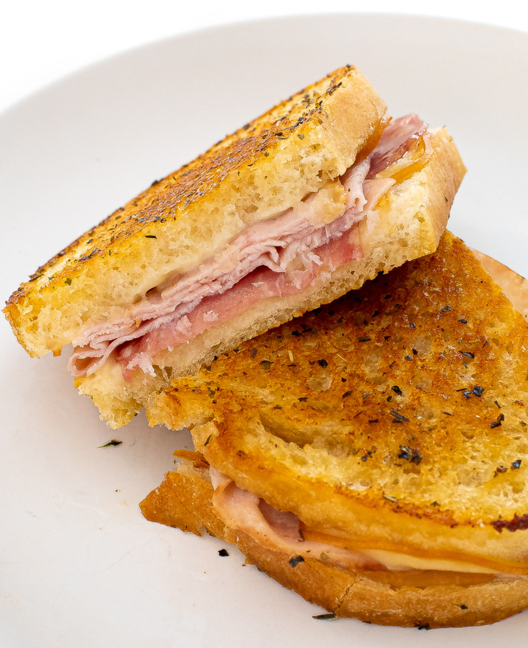 Sandwich cut in half on a white plate. 