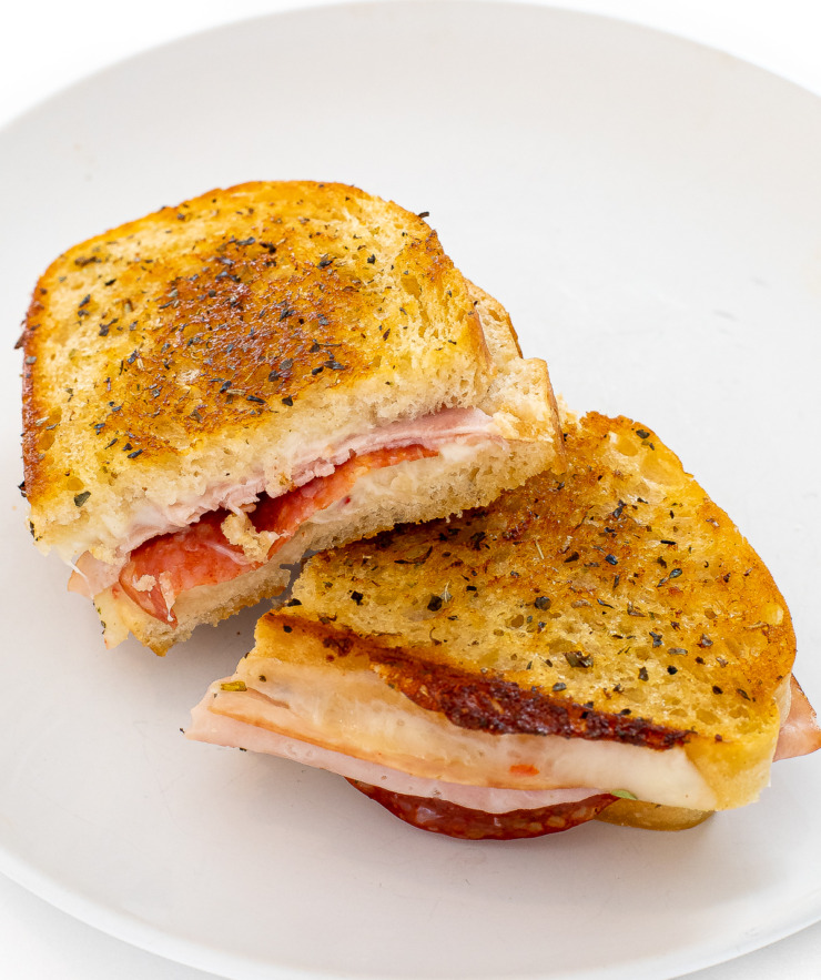 Grilled cheese cut in half on a white plate. 