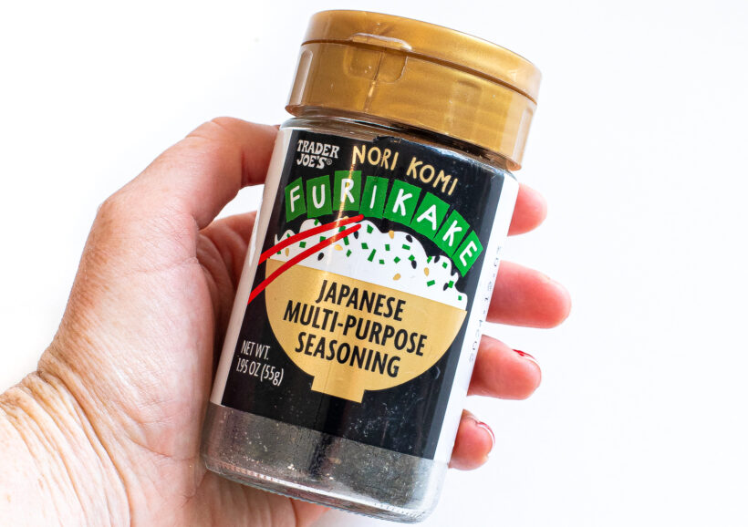 Hand holding a container of furikake Japanese seasoning.