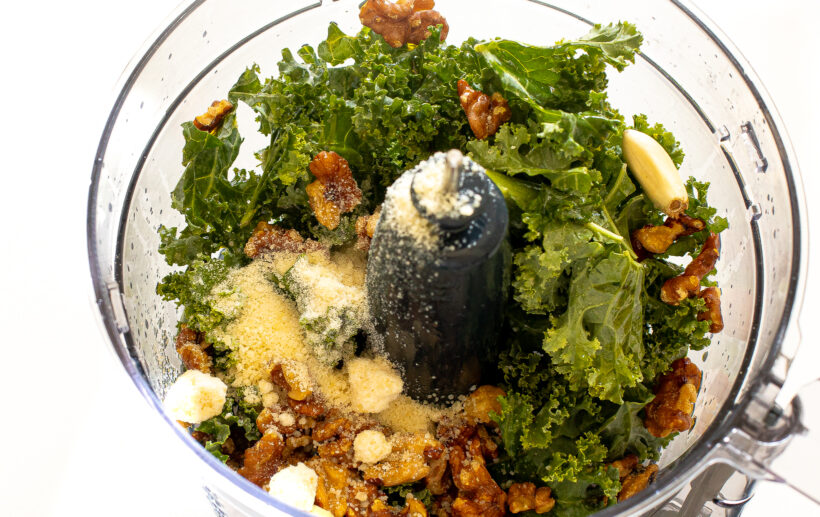 Ingredients for kale pesto in a food processor before being blended.
