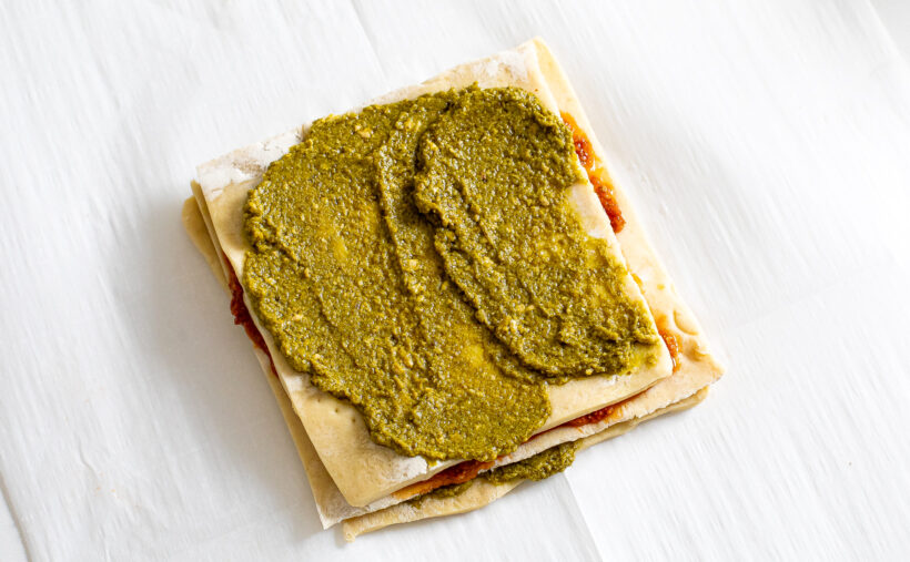 Sheets of puff pastry stacked on top of each other with layers of pesto in between. 