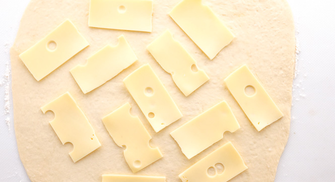topping dough with sliced Swiss cheese