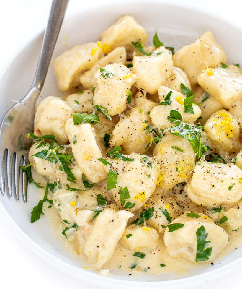 Gnocchi in a bowl in a creamy sauce with a fork on the side. 