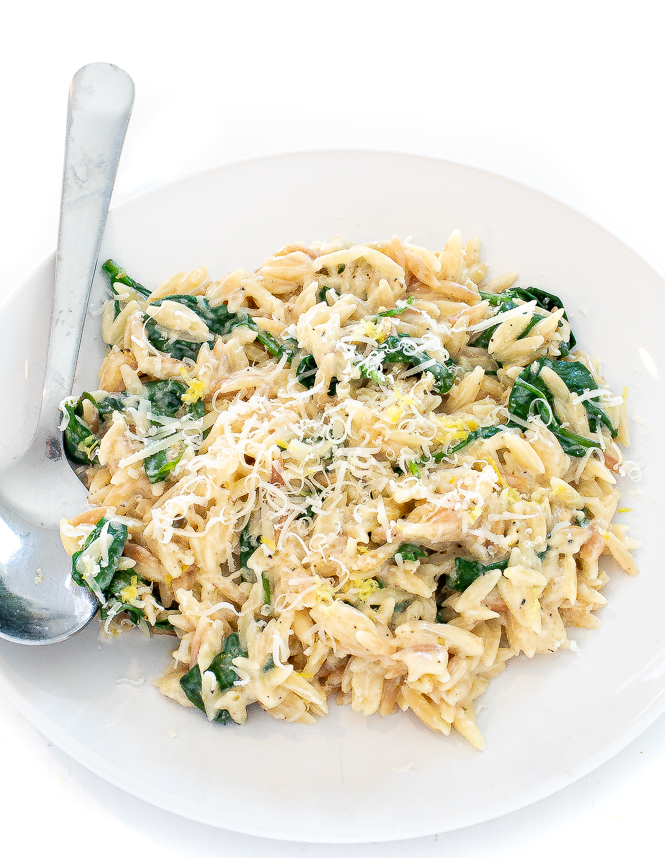 Lemon spinach orzo in a white bowl with a silver spoon.