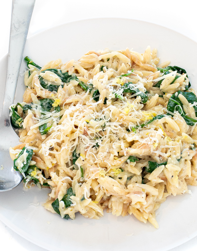 Lemon spinach orzo in a white bowl with a silver spoon.