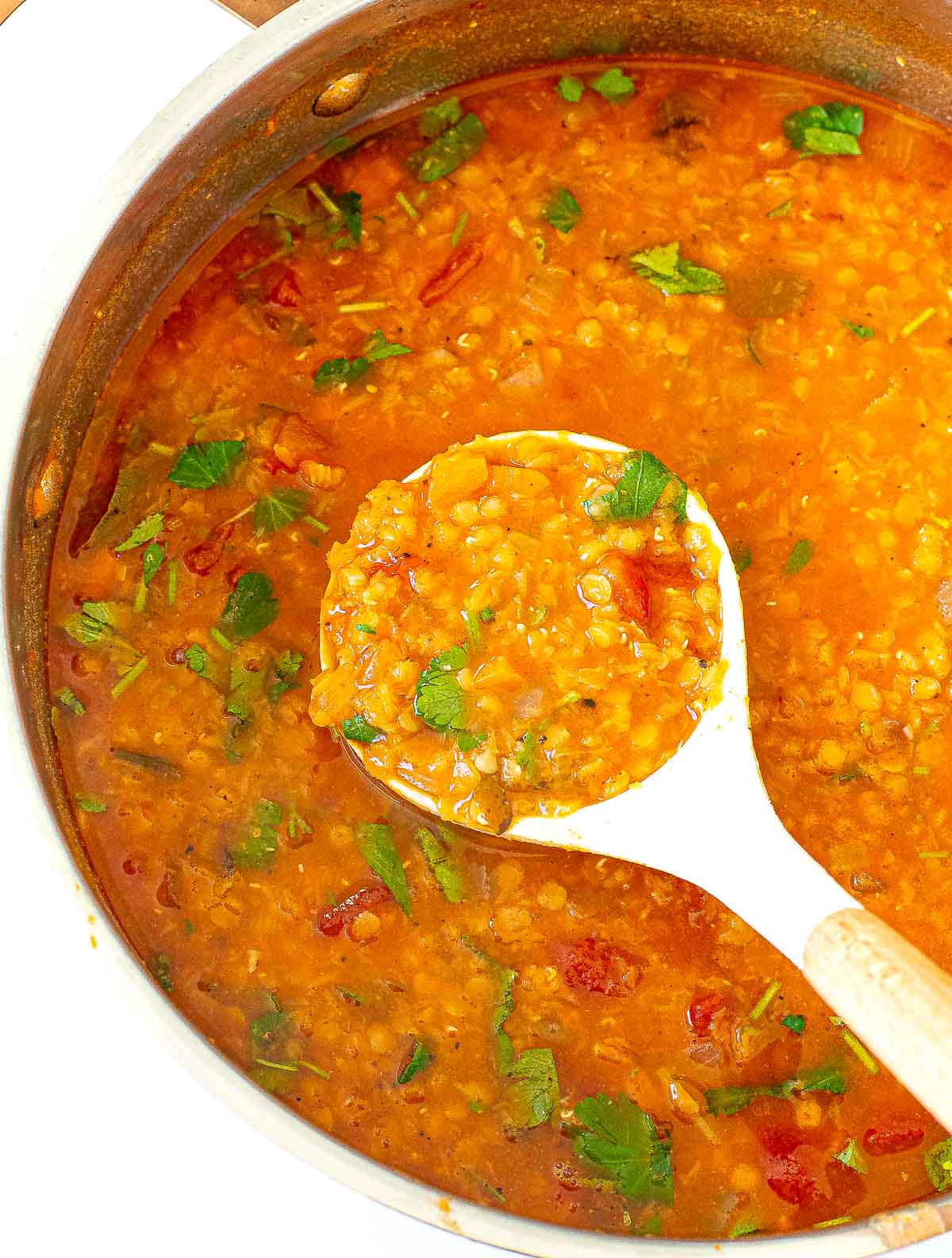 ladling lentil soup out of pot