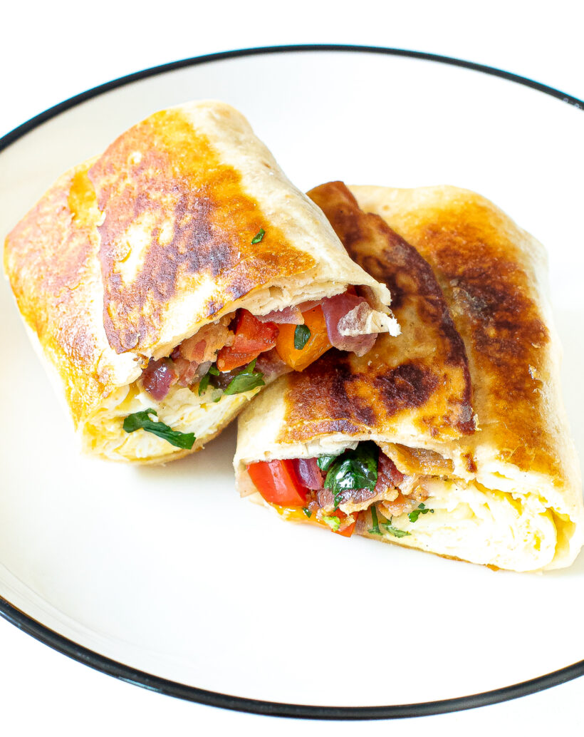 Two breakfast burrito halves on a white plate.