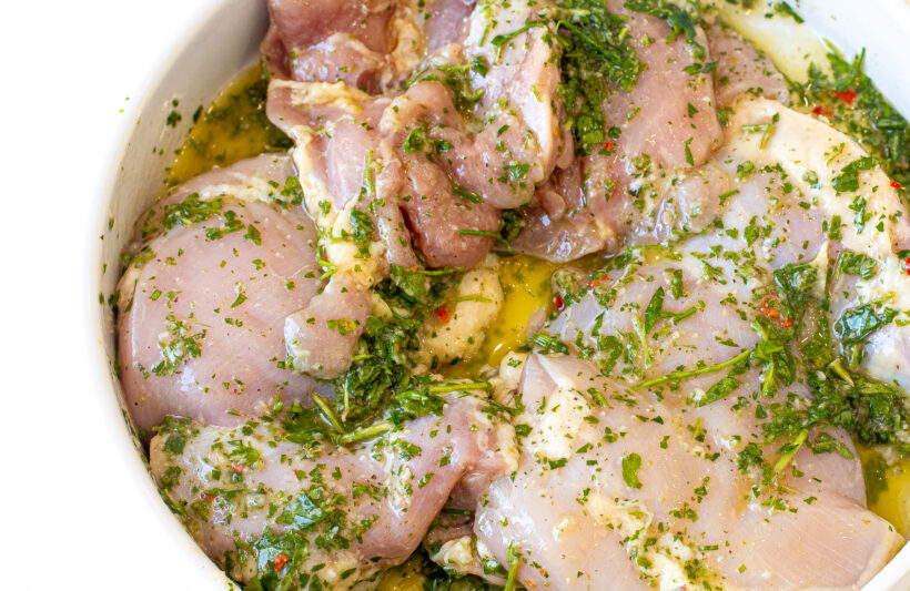 Chicken thighs marinating in chimichurri sauce.