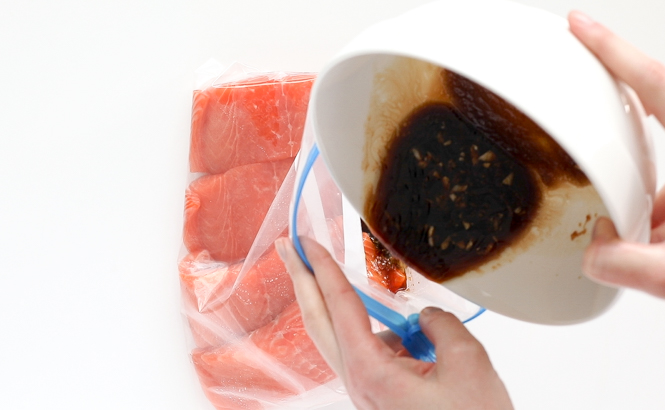 pouring teriyaki sauce in ziplock bag with salmon filets