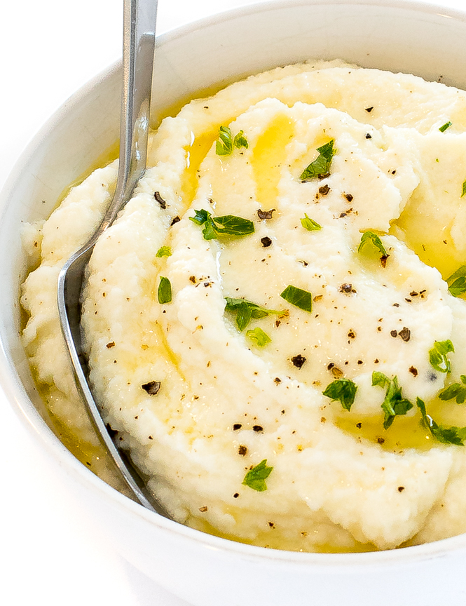 keto cauliflower mashed potatoes in a white bowl with a spoon.