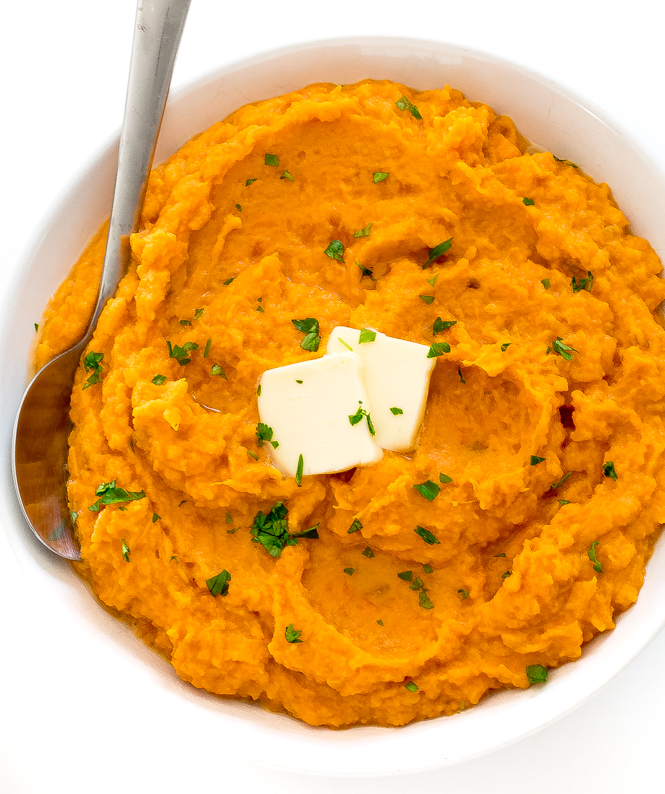 mashed potatoes in white bowl with butter and fresh parsley on top